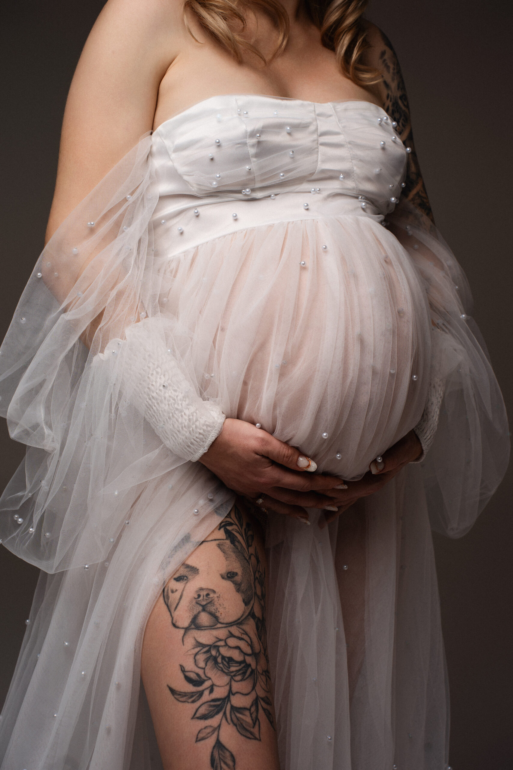 Detailaufnahme eines Babybauchs in einem eleganten Tüllkleid bei einem Schwangerschaftsshooting in Ulm.
