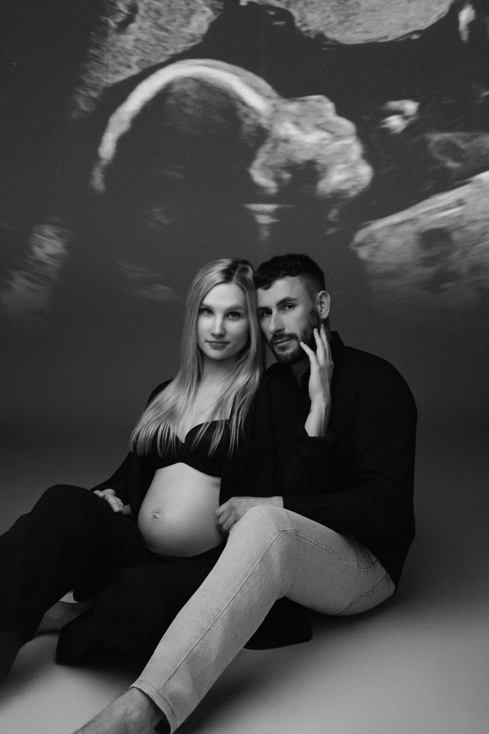 Werdende Eltern vor einer Ultraschallprojektion bei einem kreativen Babybauchshooting in Ulm.