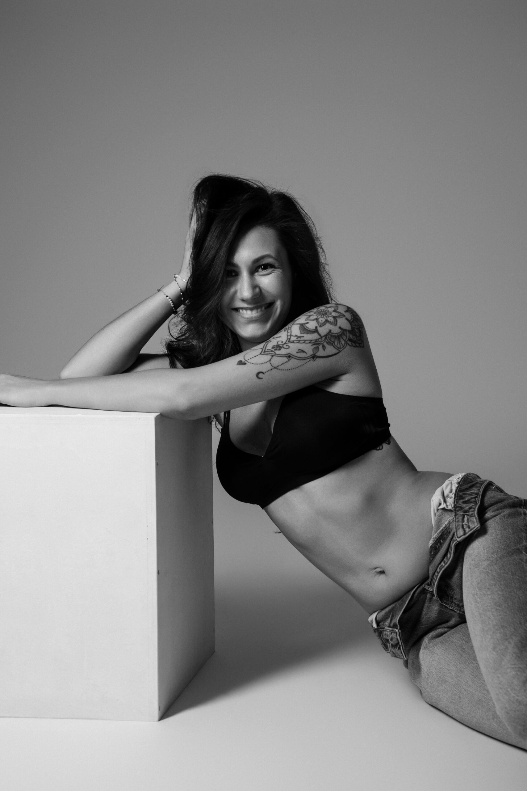 Selbstbewusste Frau in Jeans und schwarzem BH bei einem modernen Boudoir Shooting im Studio nahe Ulm