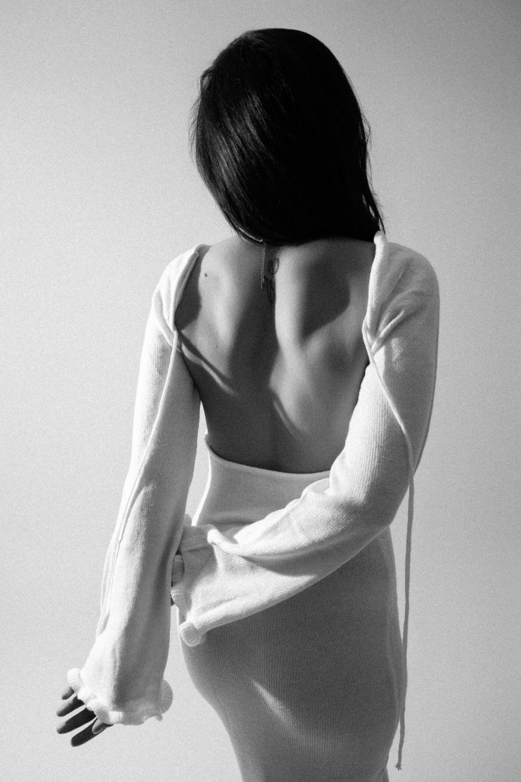 Sinnliches Boudoir Portrait einer Frau mit rückenfreiem Kleid in natürlichem Licht