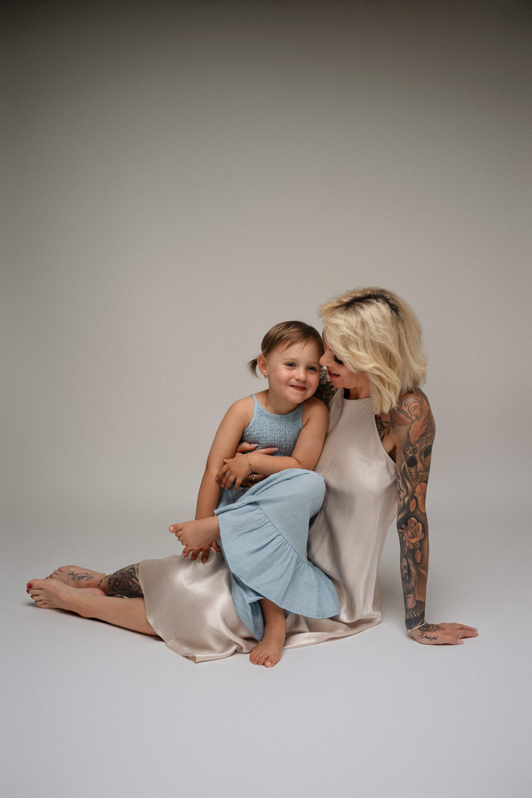 Liebevolle Mutter mit ihrer Tochter bei einem natürlichen Familienfotoshooting im hellen Fotostudio.