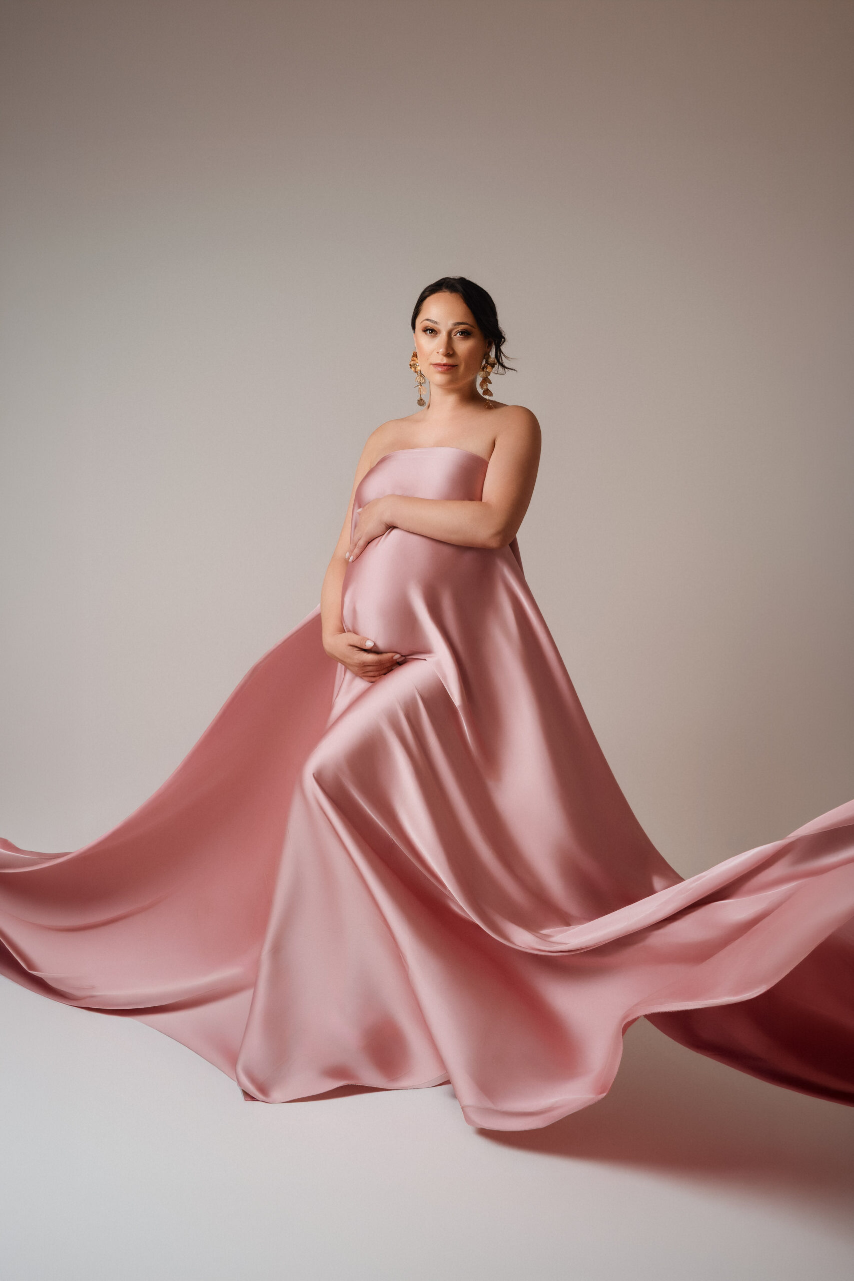 Schwangere Frau beim Maternity Shooting im Fotostudio bei Ulm mit fließendem rosa Satinstoff